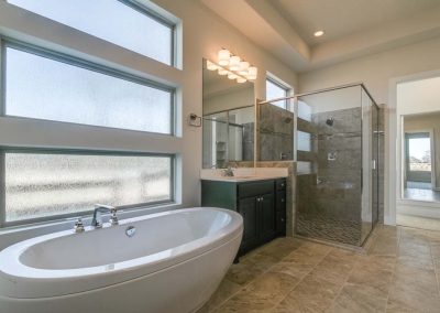 Large tub next to sink and glass shower.
